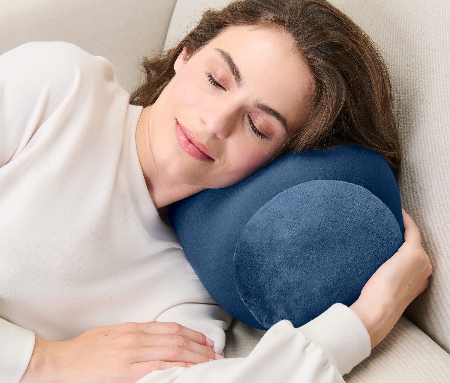 Kobieta śpi na beżowej sofie z poduszką relaksacyjną.