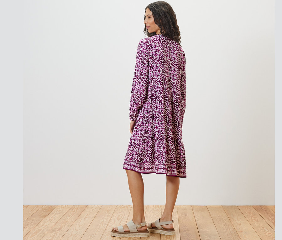 Kobieta pozuje tyłem w wzorzystej sukience z tkaniny.