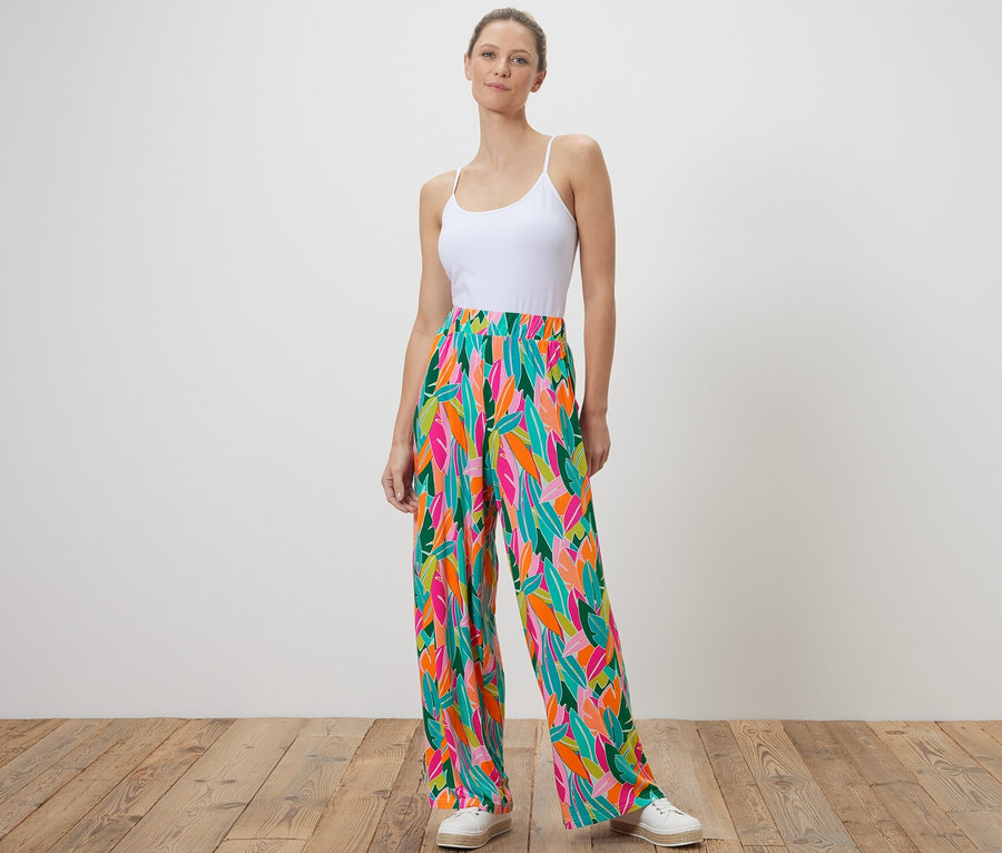Kobieta stoi i ma na sobie wzorzyste spodnie palazzo, wielobarwne.
