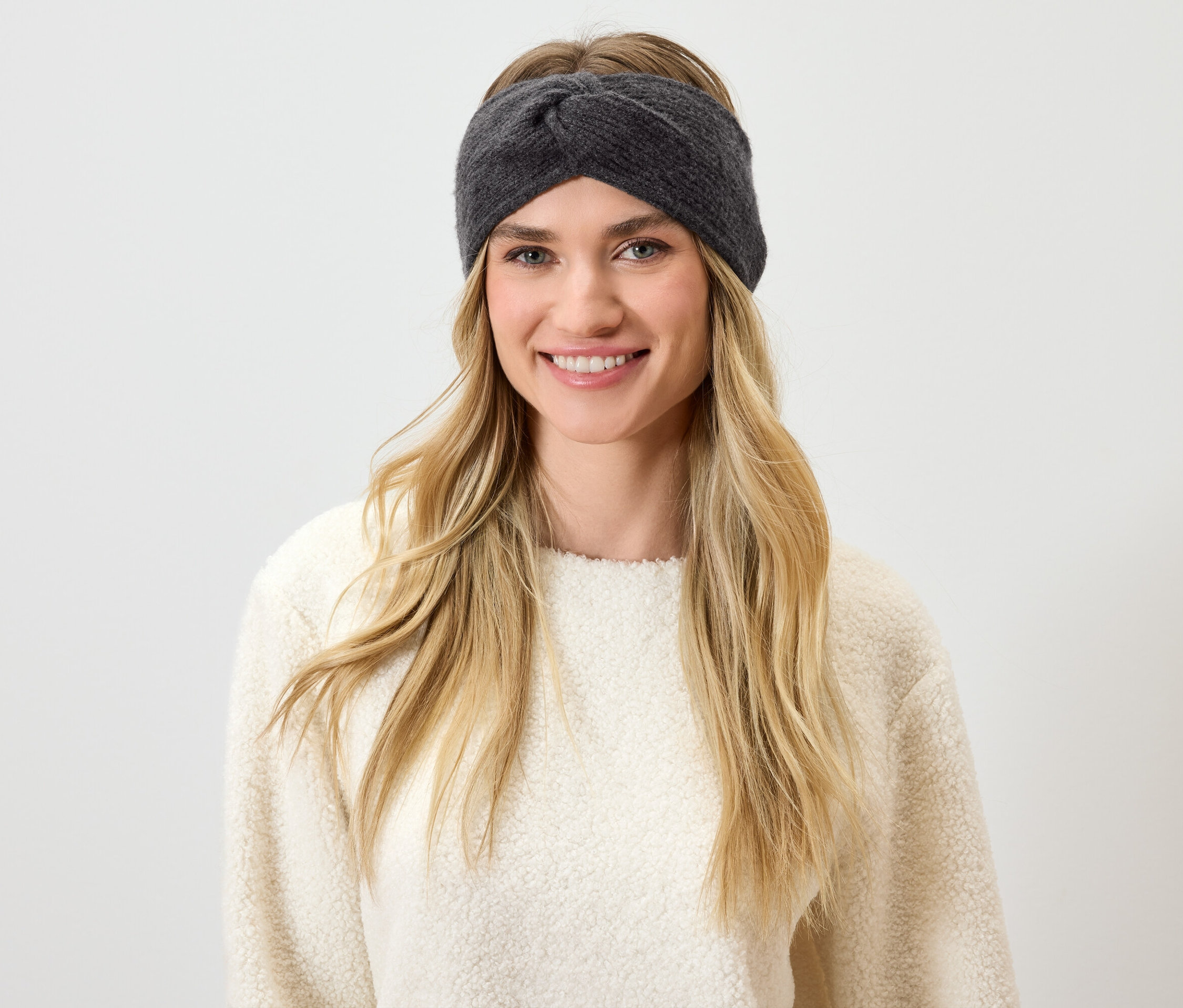 Uśmiechnięta blondynka w szarej opasce na głowie.