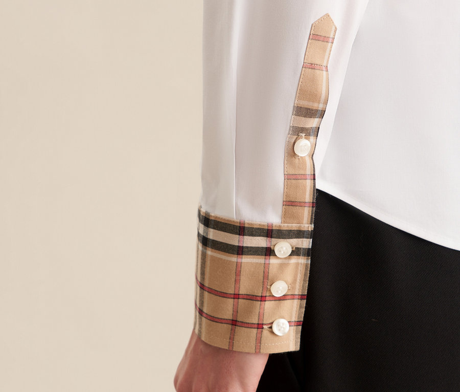 Detal białej bluzki damskiej Seidensticker z popeliny z kratkowanym detalem na mankiecie i guzikami.