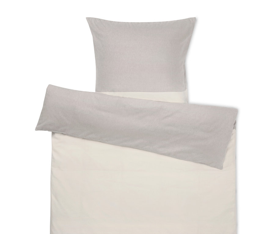 Beżowa pościel z szarą poduszką na górze.
