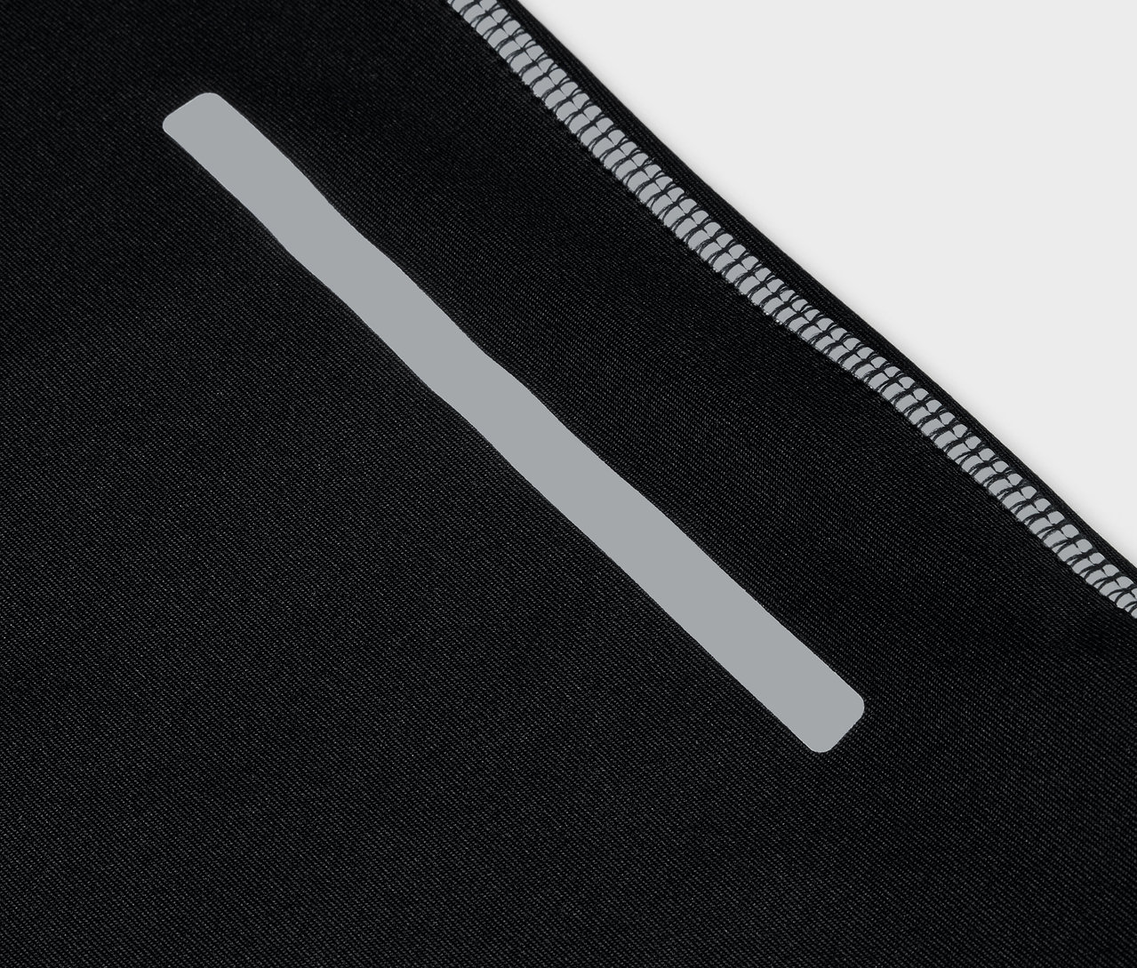 Szczegół czarnej odzieży sportowej z odblaskowym paskiem i szarym obszyciem.