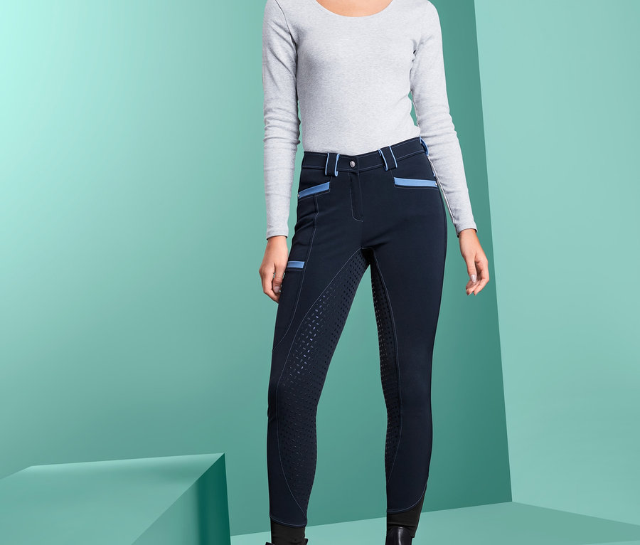 Kobieta stoi na scenie w granatowych spodniach do jazdy konnej USG i czarnych butach.