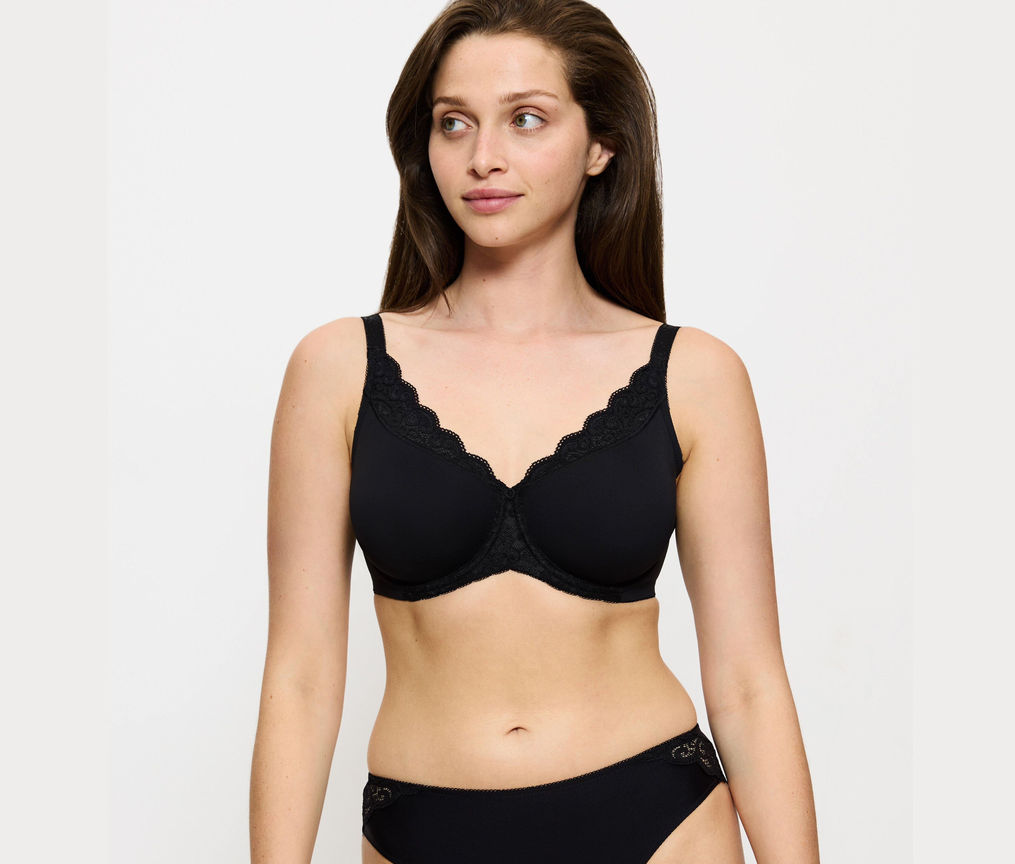 Kobieta ma na sobie czarny biustonosz Triumph Amourette Minimizer i czarne figi.