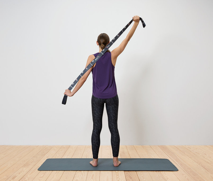 Kobieta rozciąga górną część ciała za pomocą paska do jogi.