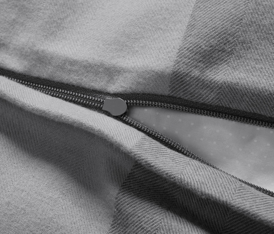 Zbliżenie na szarą poszwę na kołdrę z rozpiętym zamkiem błyskawicznym.
