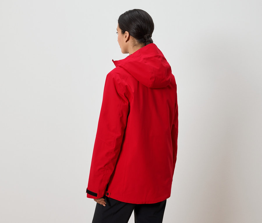 Kobieta tyłem do kamery ma na sobie czerwoną kurtkę z kapturem.