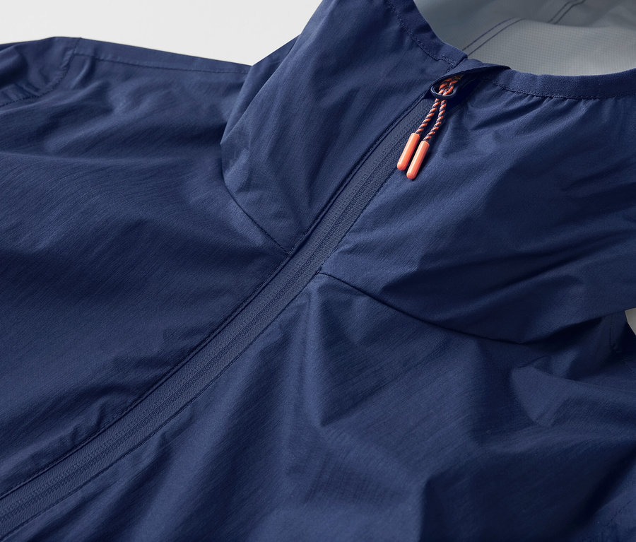 Szczegółowe ujęcie ultralekkiej kurtki przeciwdeszczowej „packable” z kapturem i zamkiem błyskawicznym.