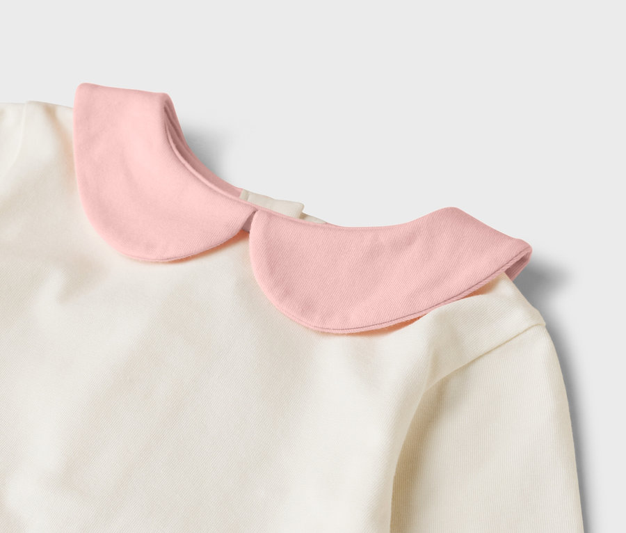 Szczegółowy widok kremowej bluzki z różowym kołnierzykiem.
