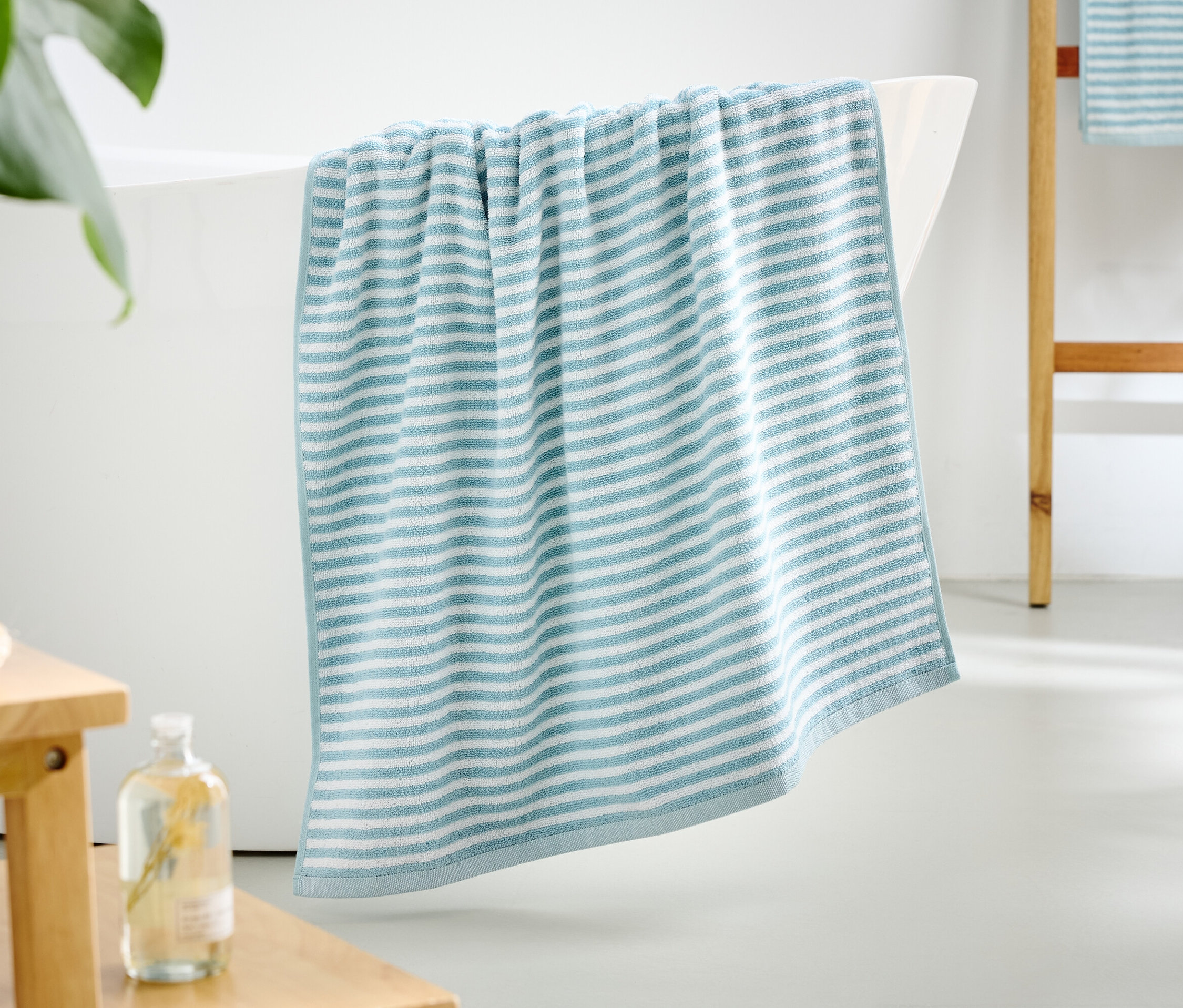 Niebiesko-biały ręcznik w paski zwisa z krawędzi wanny.