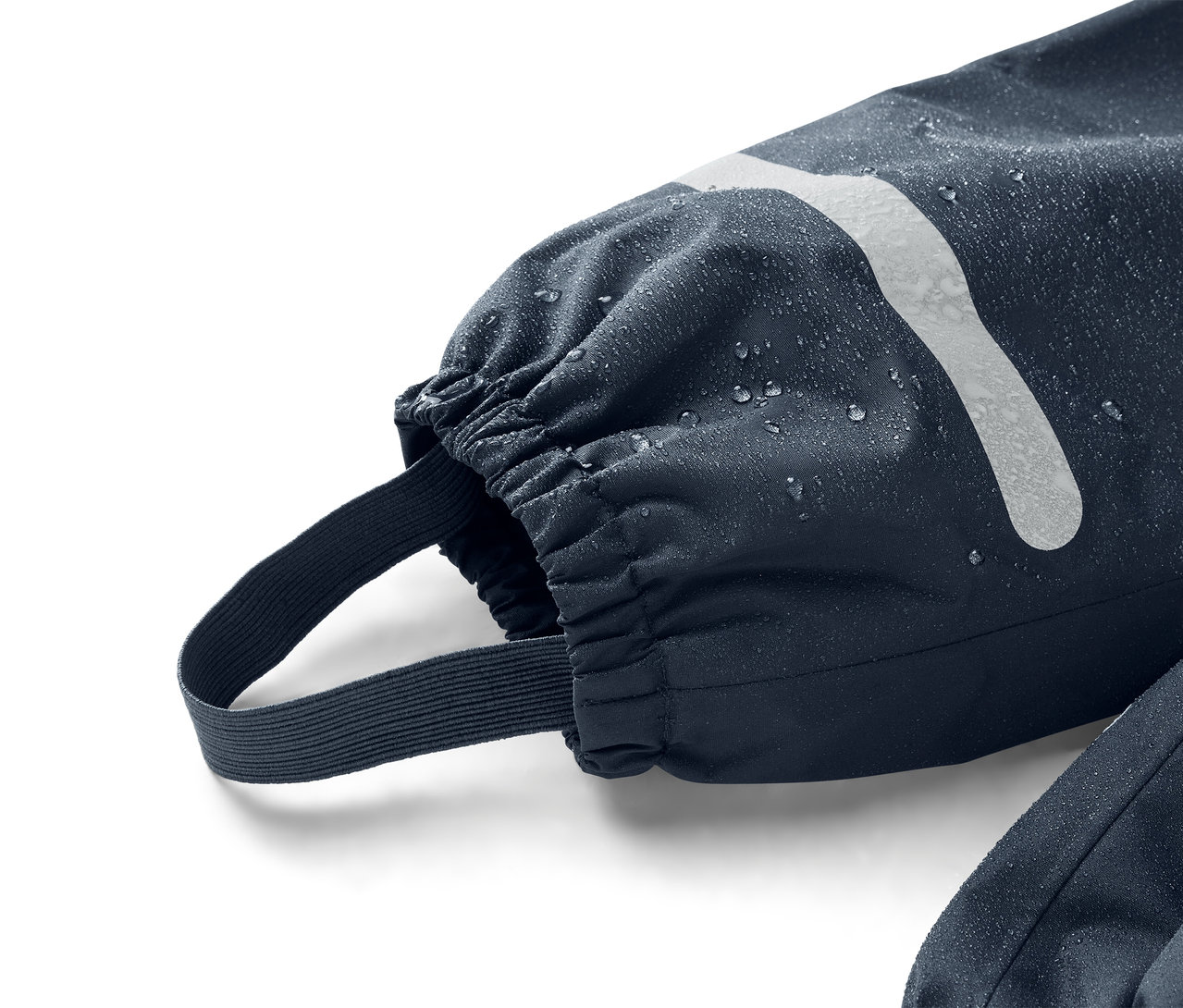 Zbliżenie granatowego rękawa z elastycznym mankietem i paskiem na stopę, pokrytego kroplami wody.