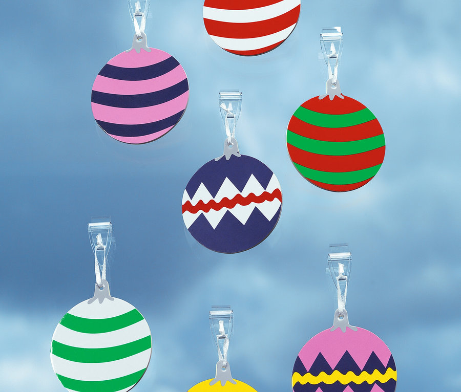 Siedem różnokolorowych, okrągłych ozdób w kształcie bombek świątecznych zawieszonych na przezroczystych klipsach na niebieskim tle.
