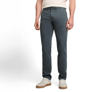 Osoba w ciemnoszarych spodniach chino, jasnym T-shircie i jasnoszarych sneakersach z białymi paskami.