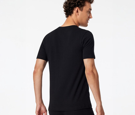Mężczyzna od tyłu, lekko obrócony, ma na sobie czarny T-shirt SCHIESSER i czarną bieliznę.