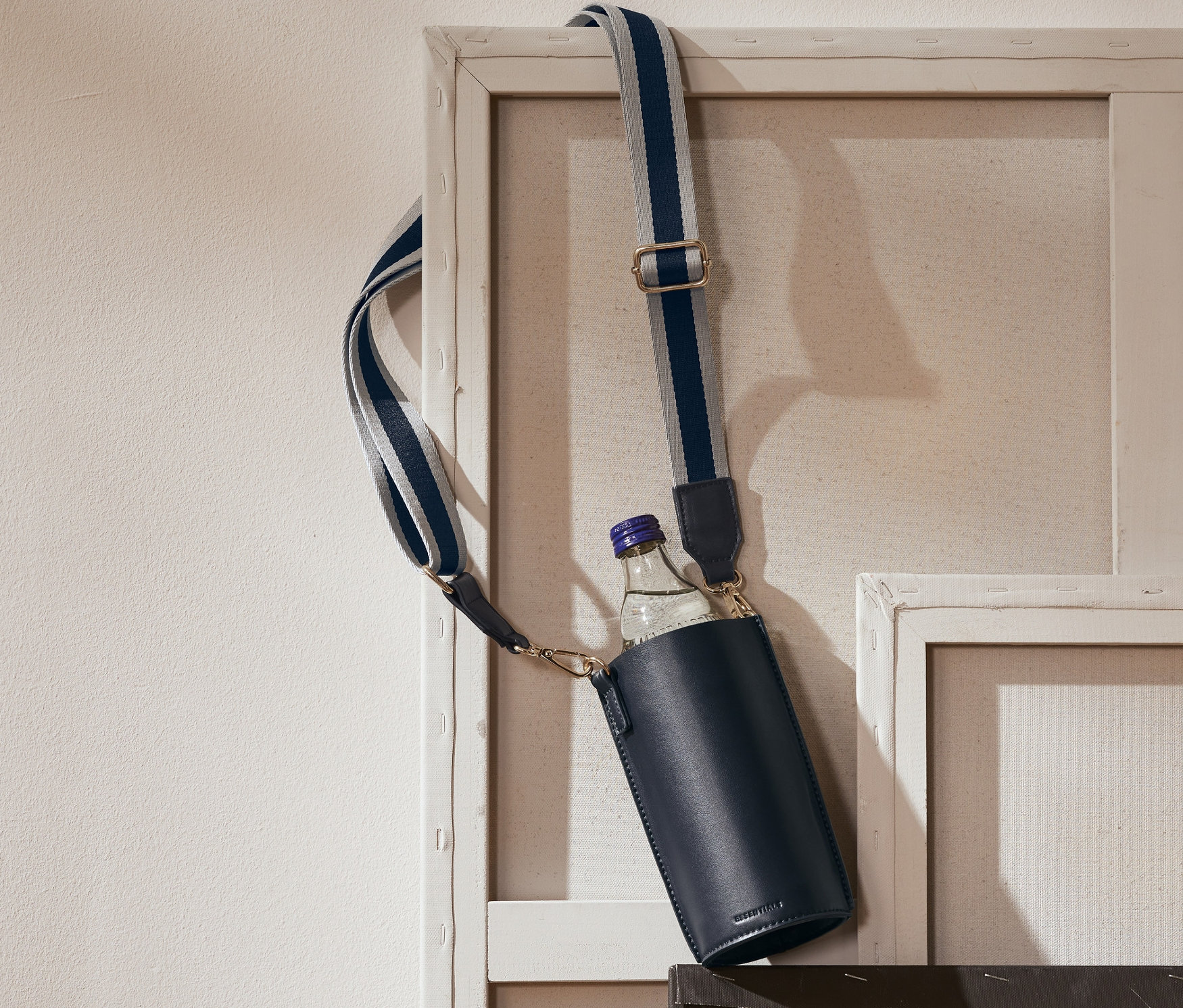 Granatowa torba na butelkę wisi na ramie obrazu.