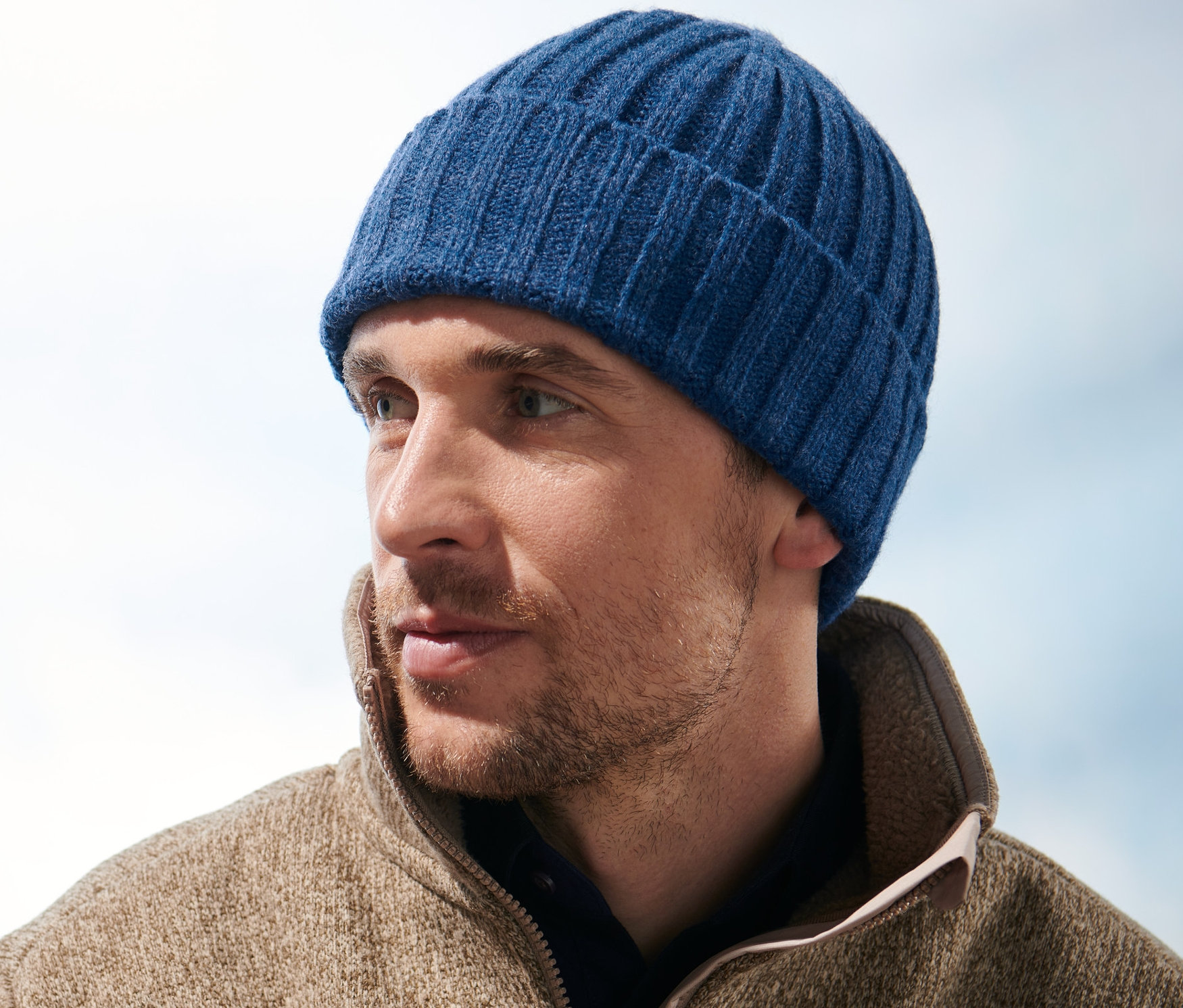 Mężczyzna w czapce z dzianiny patrzy w prawo.