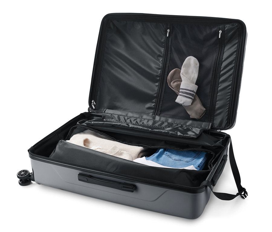 Otwarta duża walizka twarda z recyklingu z ubraniami w środku.