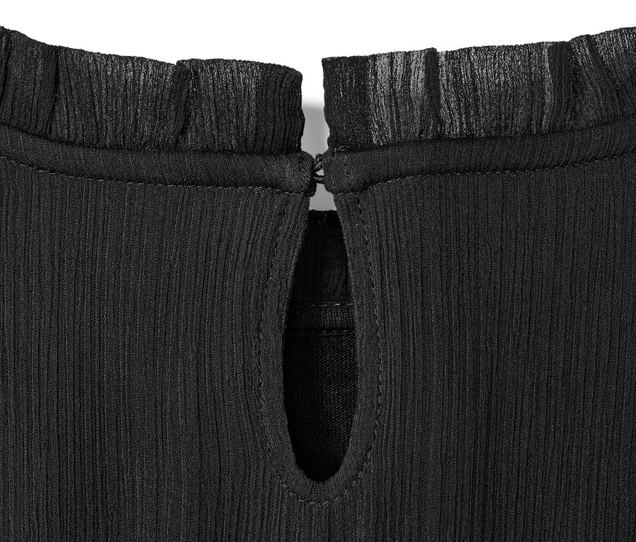 Szczegół sukienki szyfonowej dziecięcej z falbanką przy szyi i wycięciem w kształcie łezki.