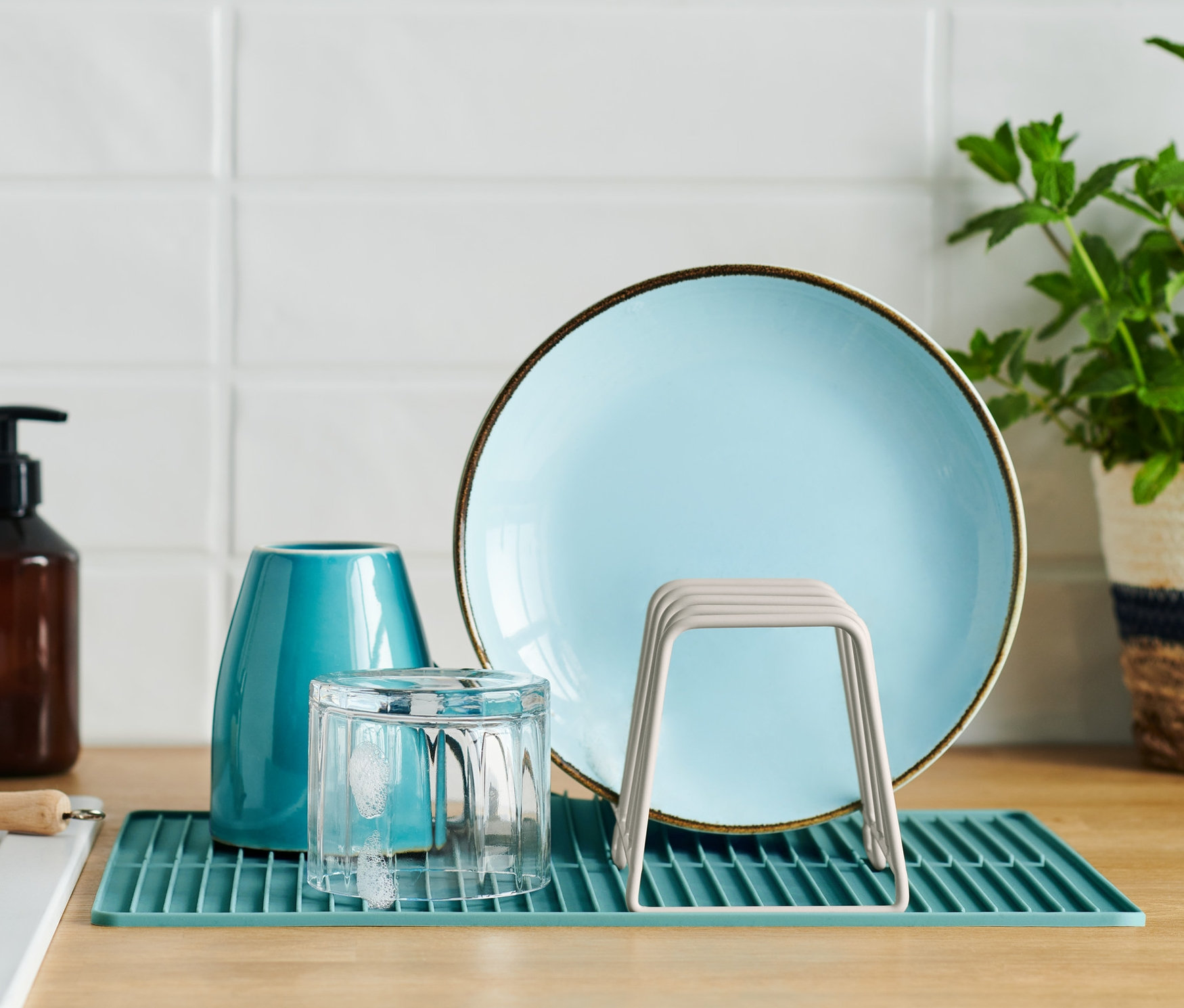 Niebieski talerz, szklanka i suszarka do naczyń z matą silikonową na blacie kuchennym.