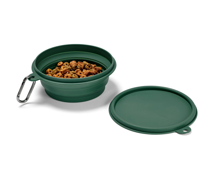 Zielona składana miska na karmę z karabińczykiem, wypełniona karmą, obok leży pokrywka.
