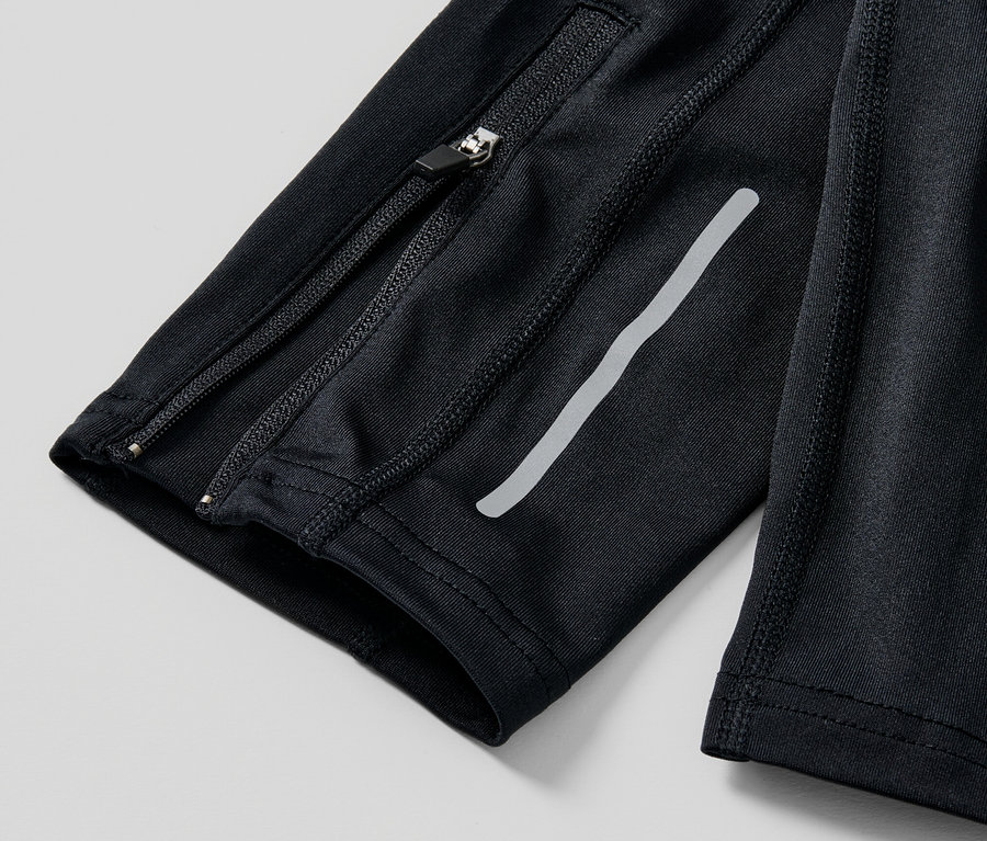 Zbliżenie na czarne legginsy do biegania z zamkiem błyskawicznym i odblaskowym paskiem.