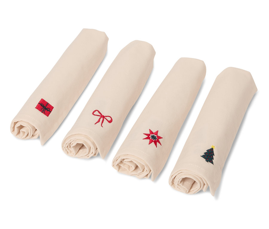 Cztery zwinięte, beżowe serwetki z motywami świątecznymi.