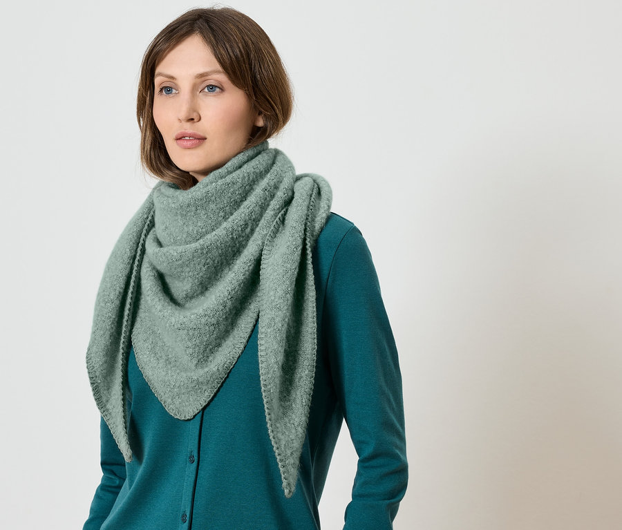 Kobieta ma na sobie zielony szal i zielony sweter.