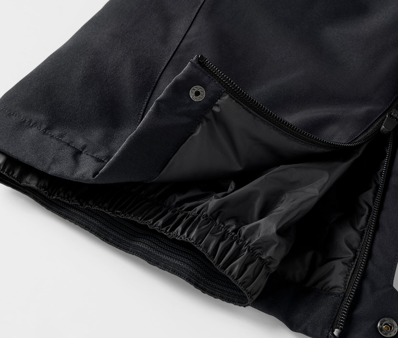 Szczegół czarnych spodni z rozpiętym zamkiem błyskawicznym i zatrzaskiem.