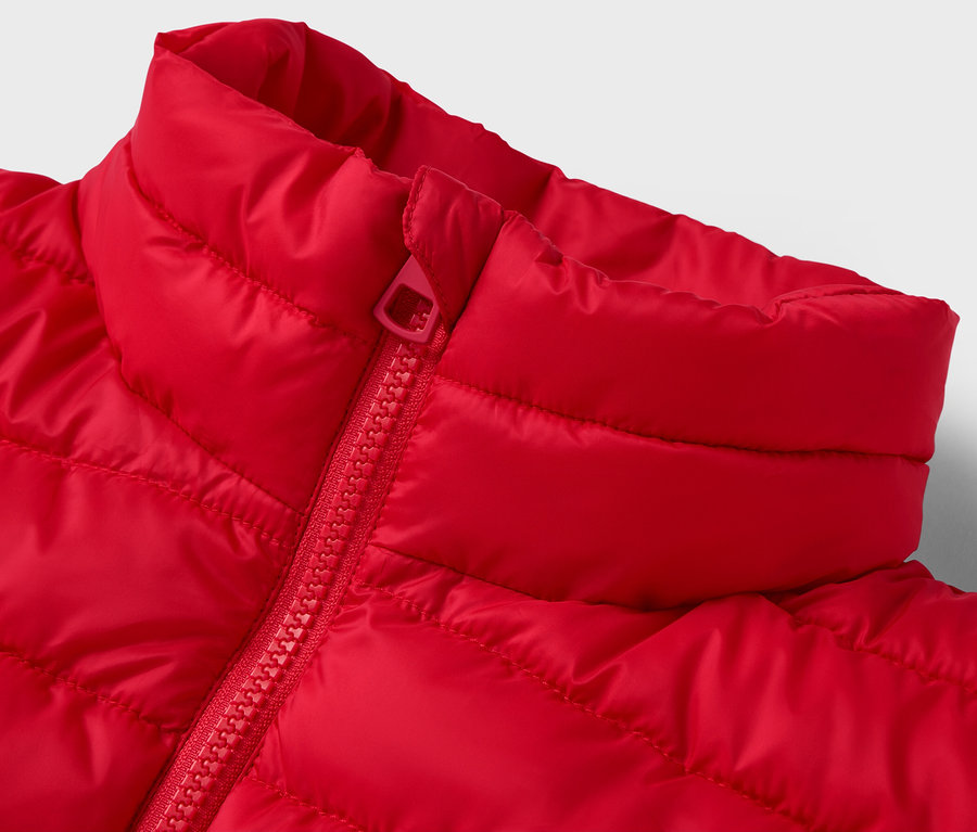 Zbliżenie na czerwoną pikowaną kurtkę z kołnierzem i zamkiem błyskawicznym.