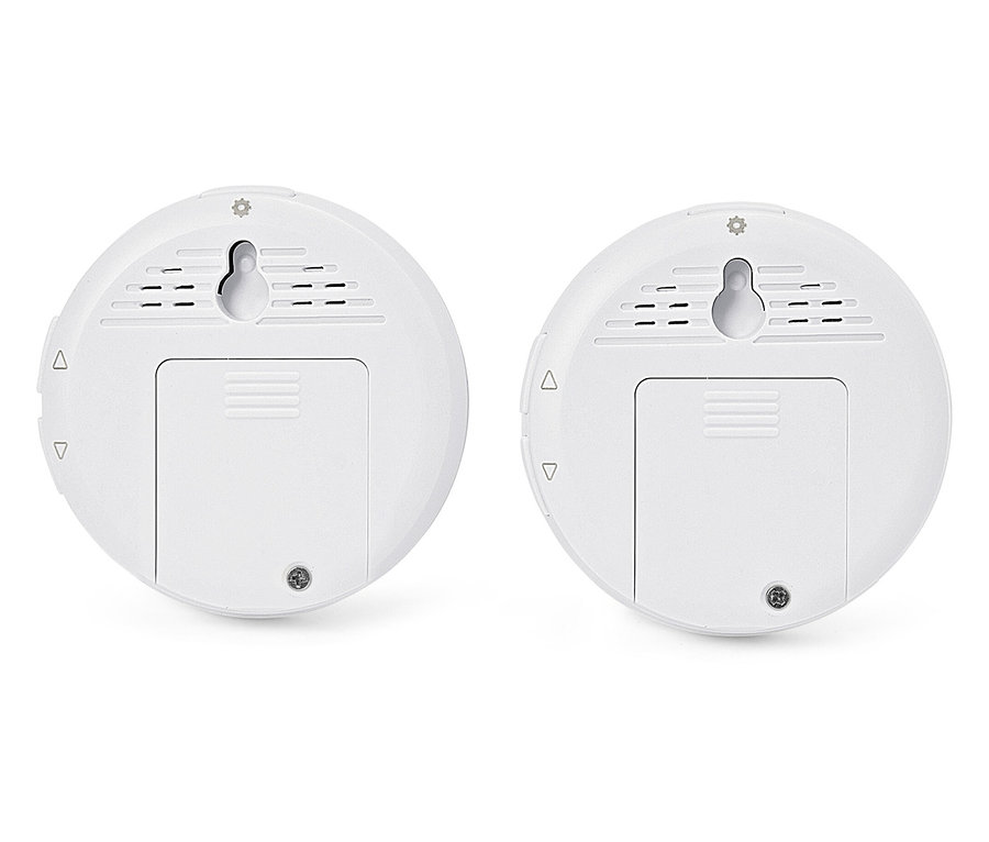 Dwa białe, okrągłe czujniki z uchwytami ściennymi i pokrywami komory baterii.