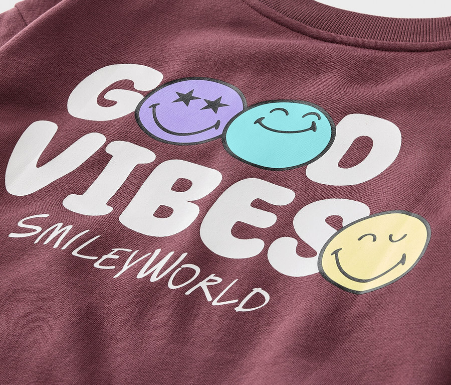 Zbliżenie na bordową bluzę SMILEYWORLD® z napisem GOOD VIBES i trzema emotikonami.
