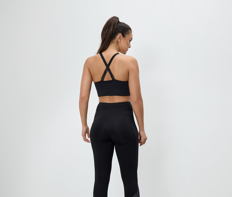 Widok z tyłu kobiety w czarnej odzieży sportowej, składającej się ze stanika sportowego i legginsów.