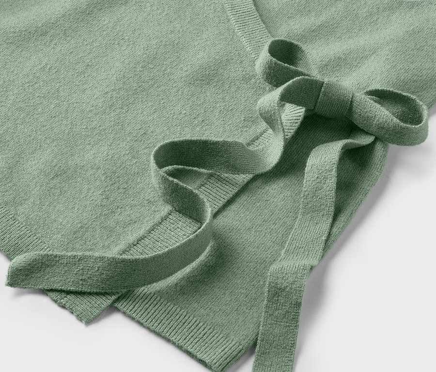 Zbliżenie jasnozielonego swetra z wiązaniem.