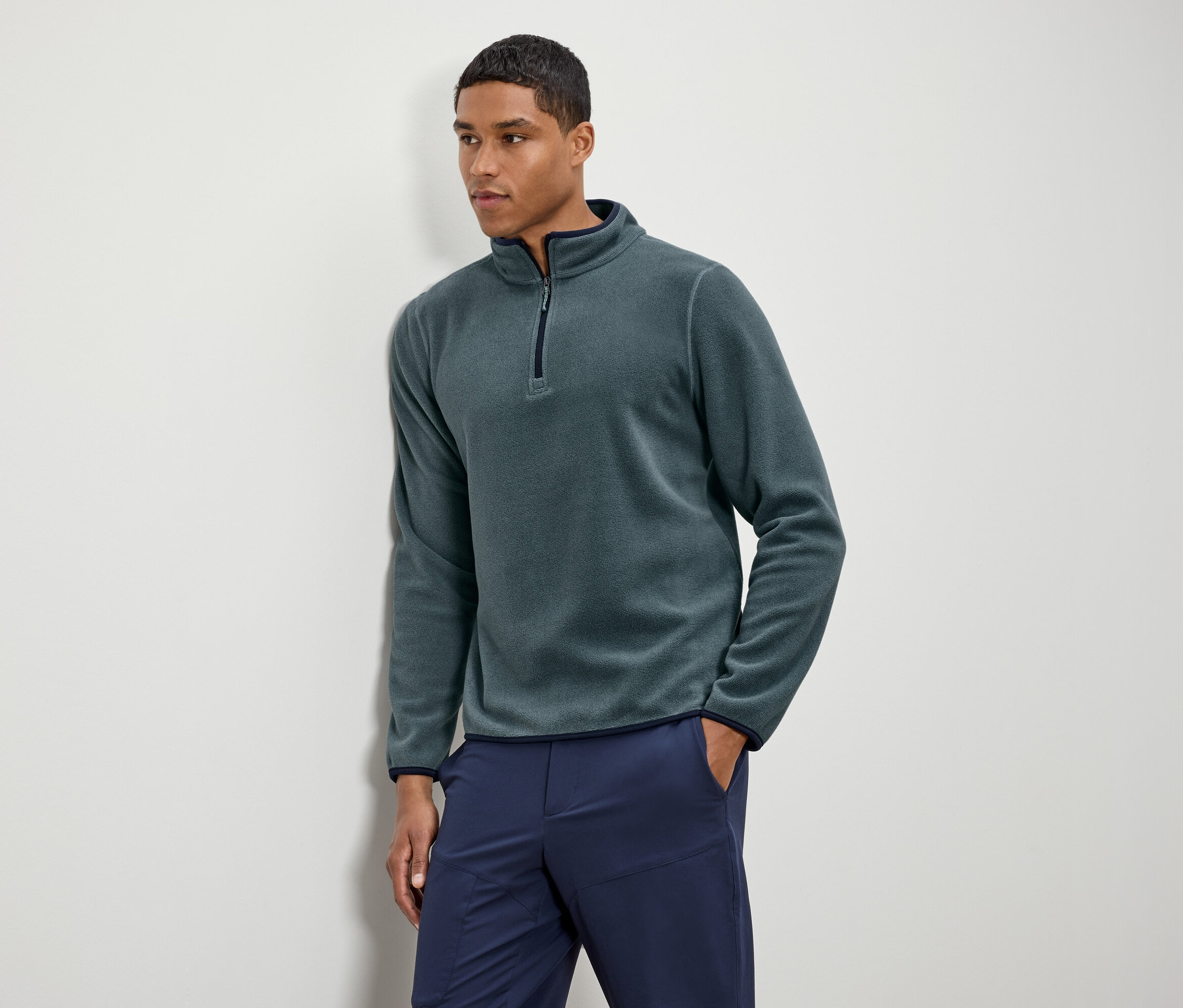 Mężczyzna ma na sobie zieloną bluzę polarową z granatowymi spodniami.