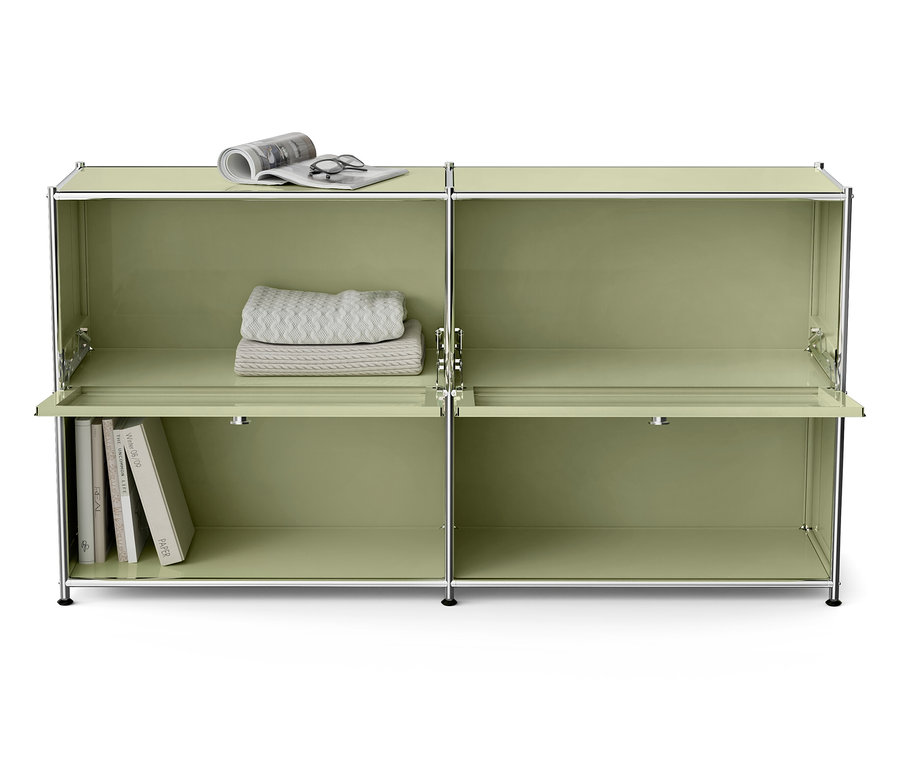 Zielona modułowa szafka z książkami, kocem, okularami i gazetą.