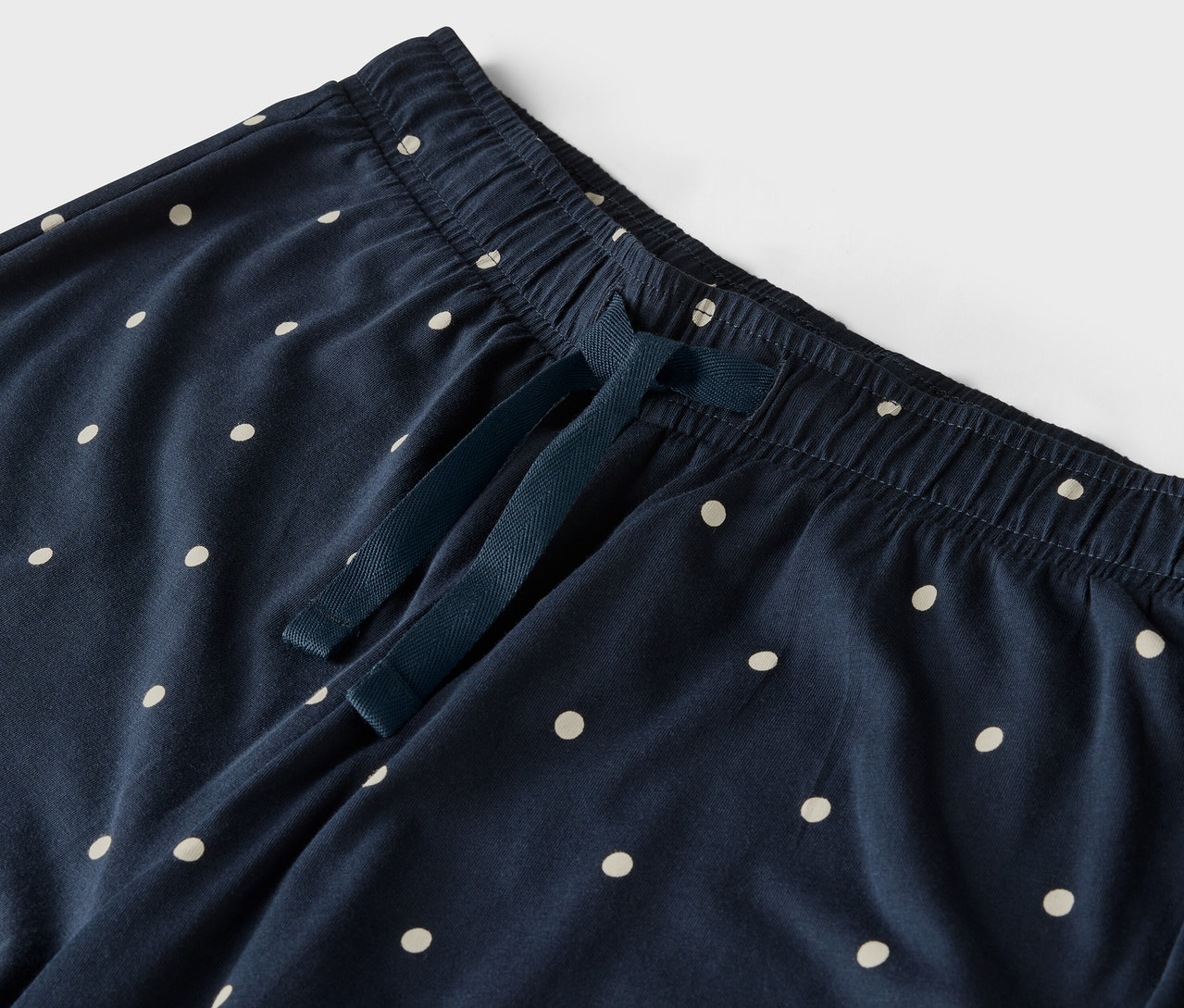 Detal granatowych spodni w białe kropki, z elastycznym pasem i sznurkiem.