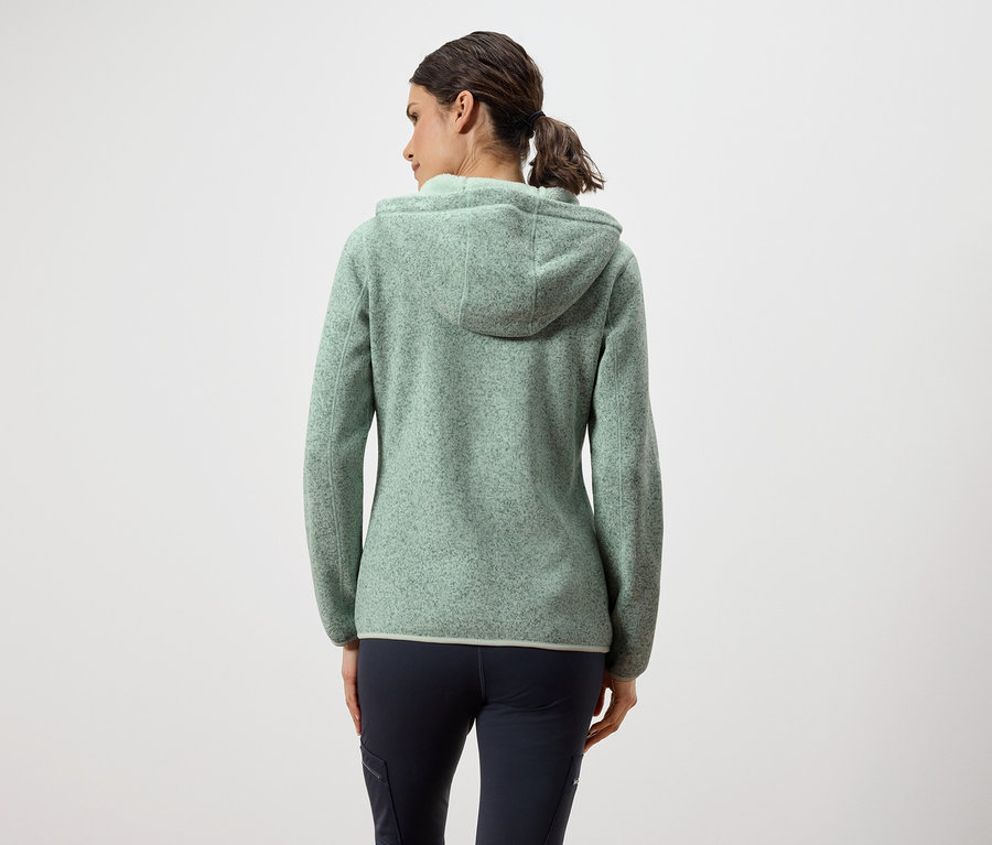 Widok z tyłu kobiety w zielonej bluzie polarowej z kapturem i granatowych spodniach.