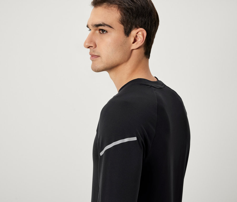 Mężczyzna z profilu w czarnej koszulce z długim rękawem i odblaskowym paskiem.