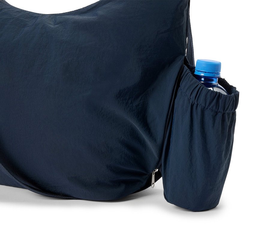Szczegółowe ujęcie granatowej torby na ramię z butelką wody w bocznej kieszeni.
