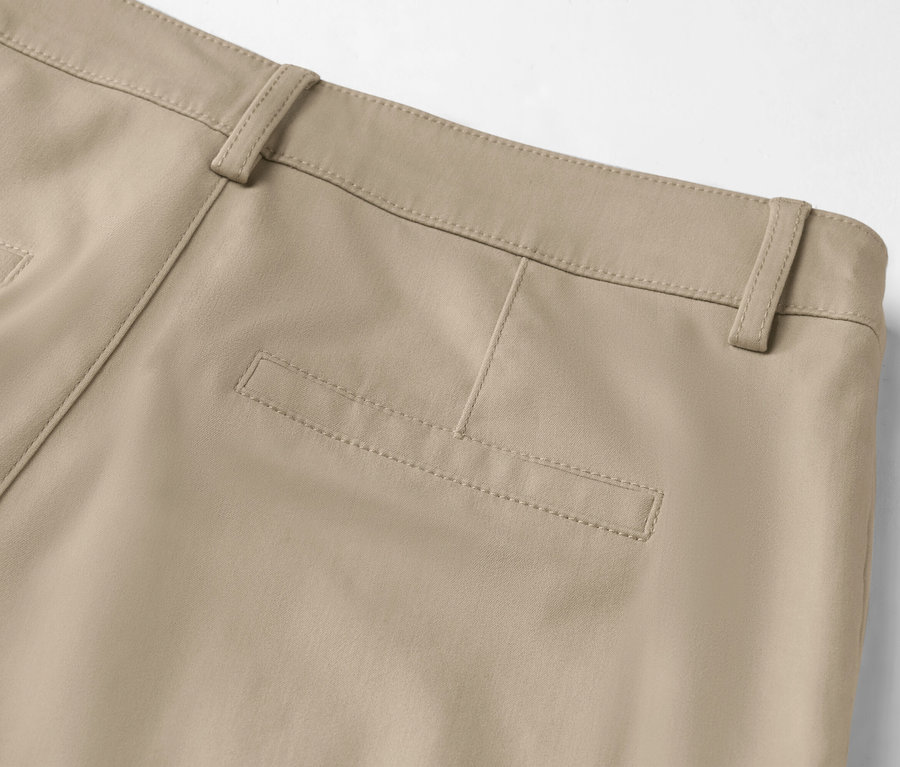 Zbliżenie na tył beżowych spodni z kieszenią na pośladku i szlufkami.