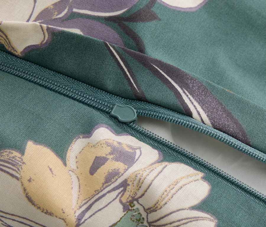 Zbliżenie na zamek błyskawiczny na zielonkawej tkaninie w kwiatowy wzór.