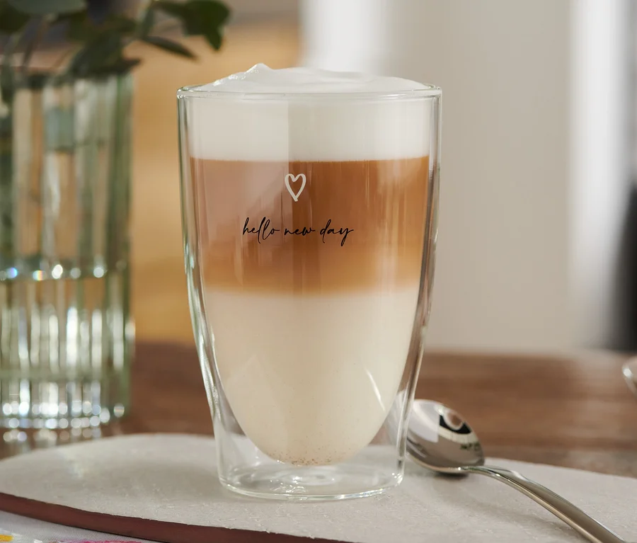 Szklanka Latte Macchiato z nadrukiem serduszka, wypełniona warstwami mleka, kawy i pianki.