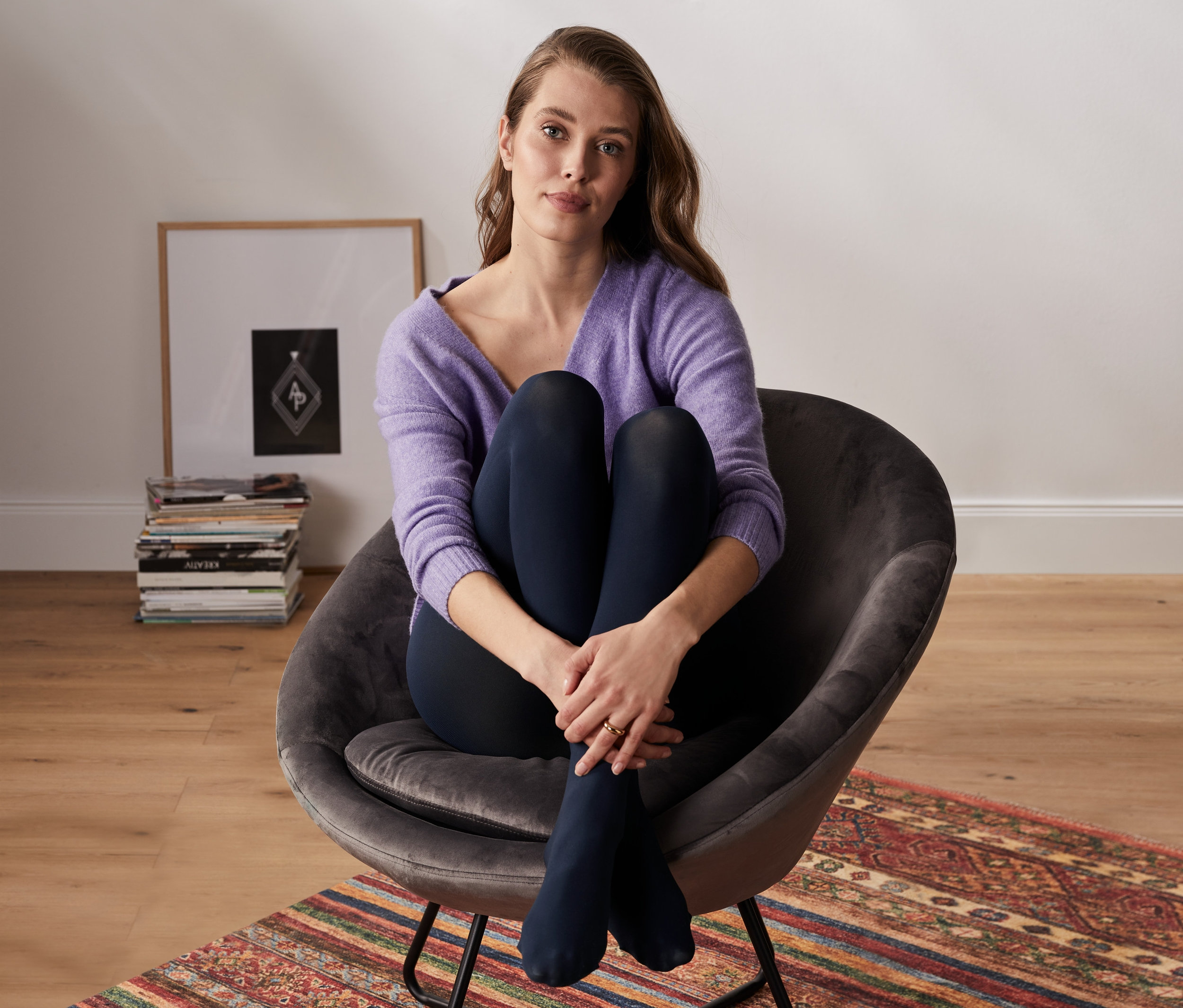 Kobieta siedzi w fotelu i ma na sobie rajstopy kryjące, 2 pary.