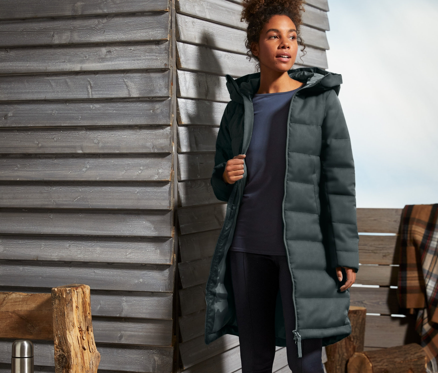 Kobieta idzie na zewnątrz w ciemnozielonym płaszczu pikowanym.