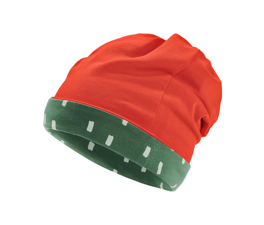 Zbliżenie na dwustronną czapkę: pomarańczowa na zewnątrz, zielona w białe kropki wewnątrz.