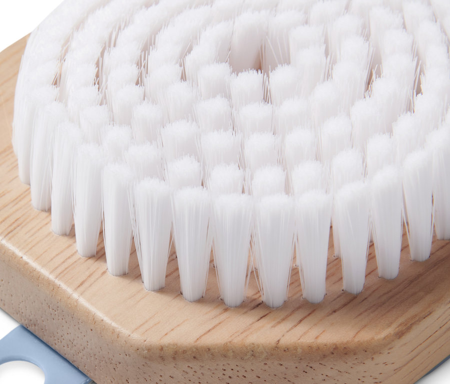 Zbliżenie szczoteczki do twarzy z białym włosiem i drewnianą rączką.