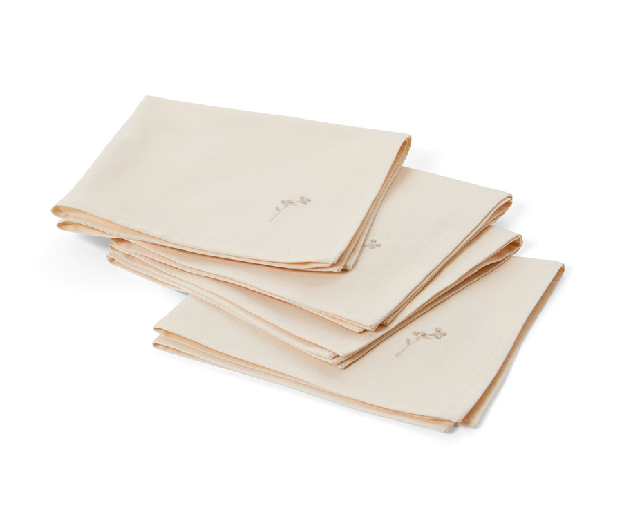 Cztery kremowe serwetki z haftem leżą złożone na sobie.