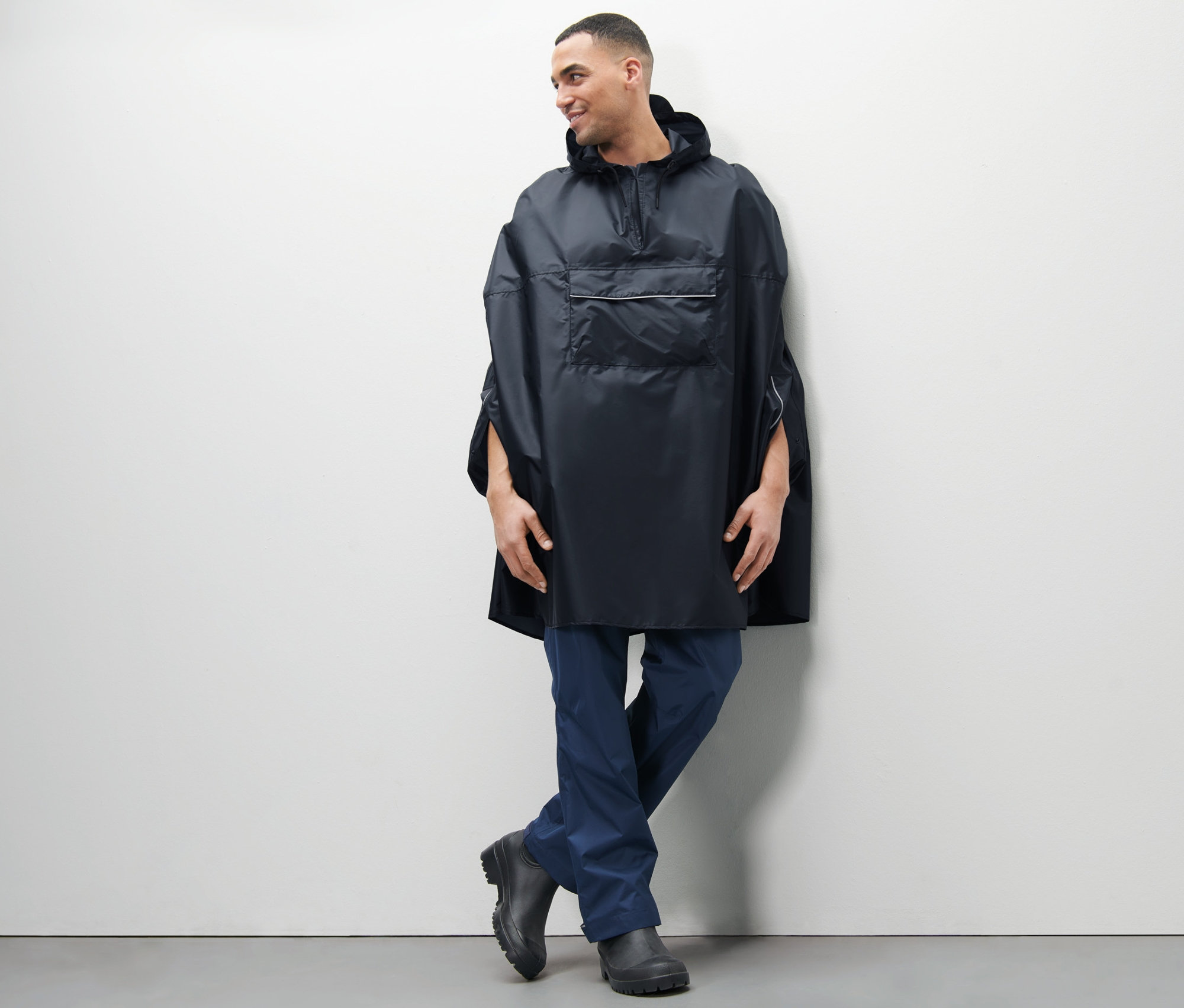 Mężczyzna pozuje w niebieskim ponczo przeciwdeszczowym uniseks.