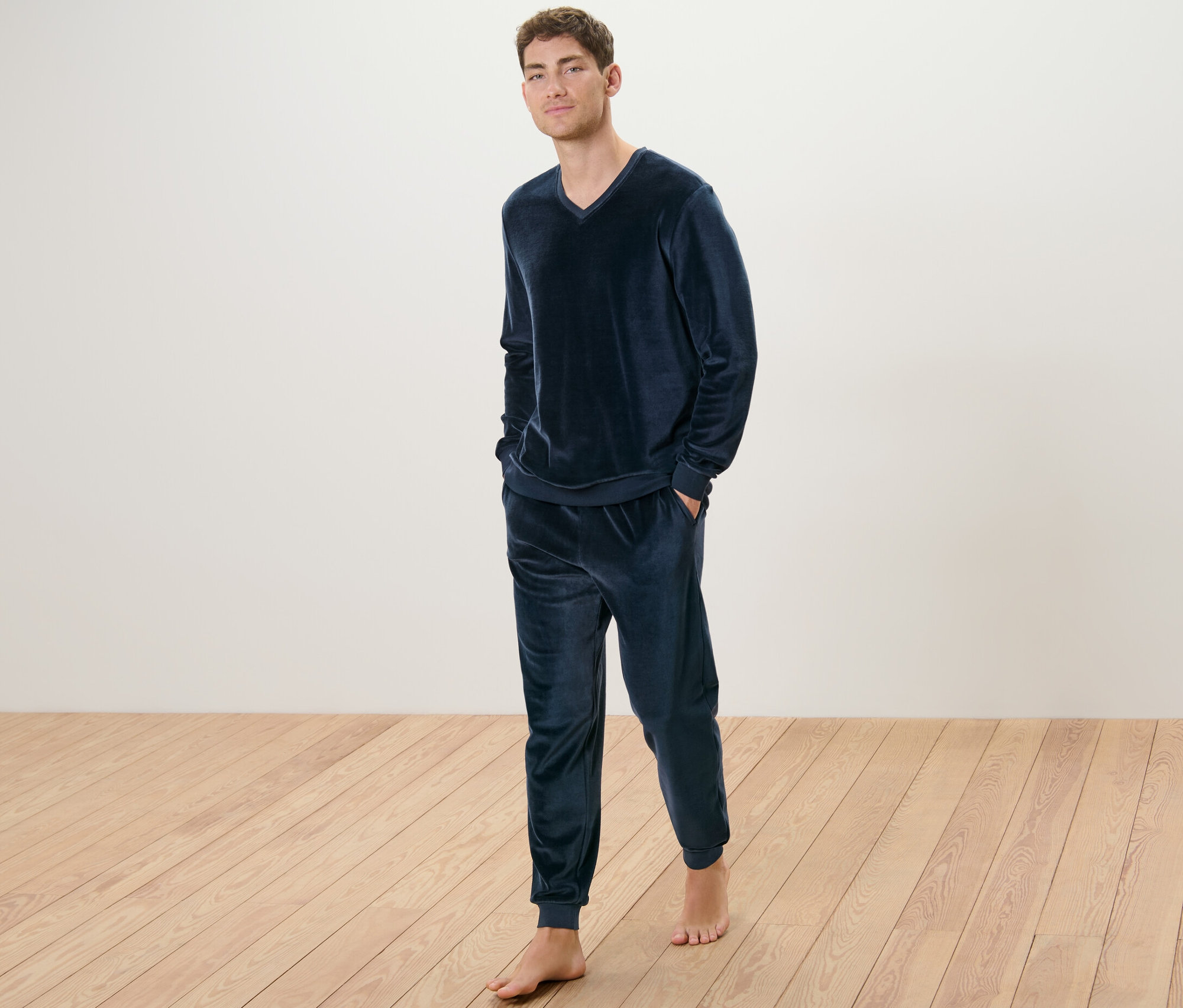 Mężczyzna stoi boso w piżamie z weluru.